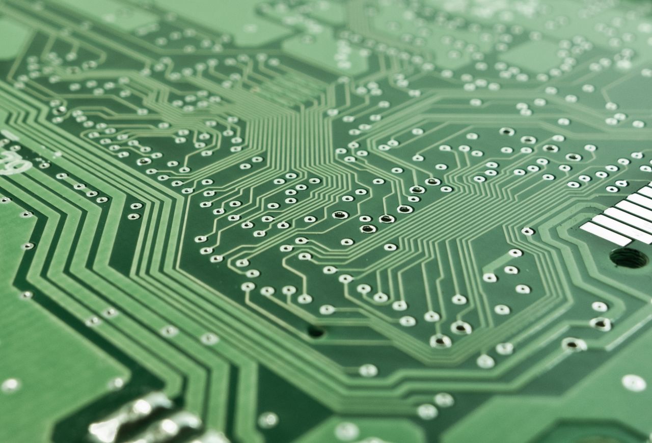 services-04 Detailed view of a green circuit board with complex patterns and pathways.