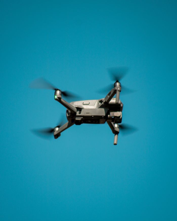 heros-img A modern drone flying against a clear blue sky, showcasing aviation technology.