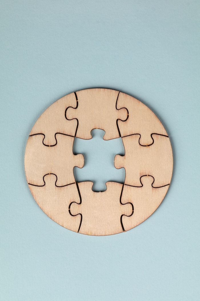 services-02 A minimalist round wooden puzzle with a missing piece on a light blue background.