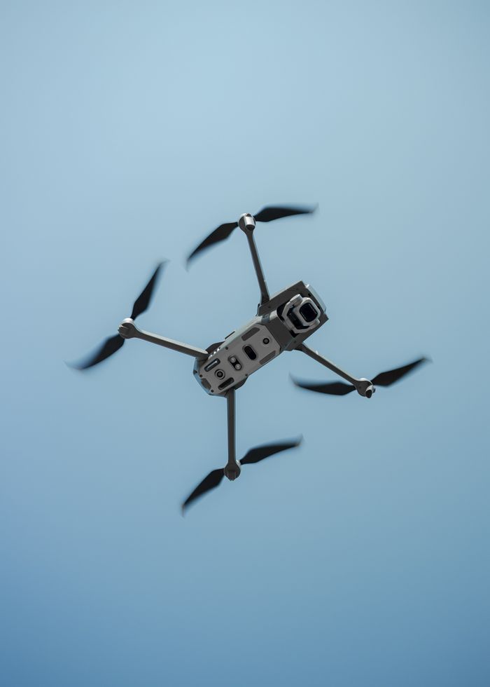 about-us A high-definition capture of a drone flying against a clear blue sky.