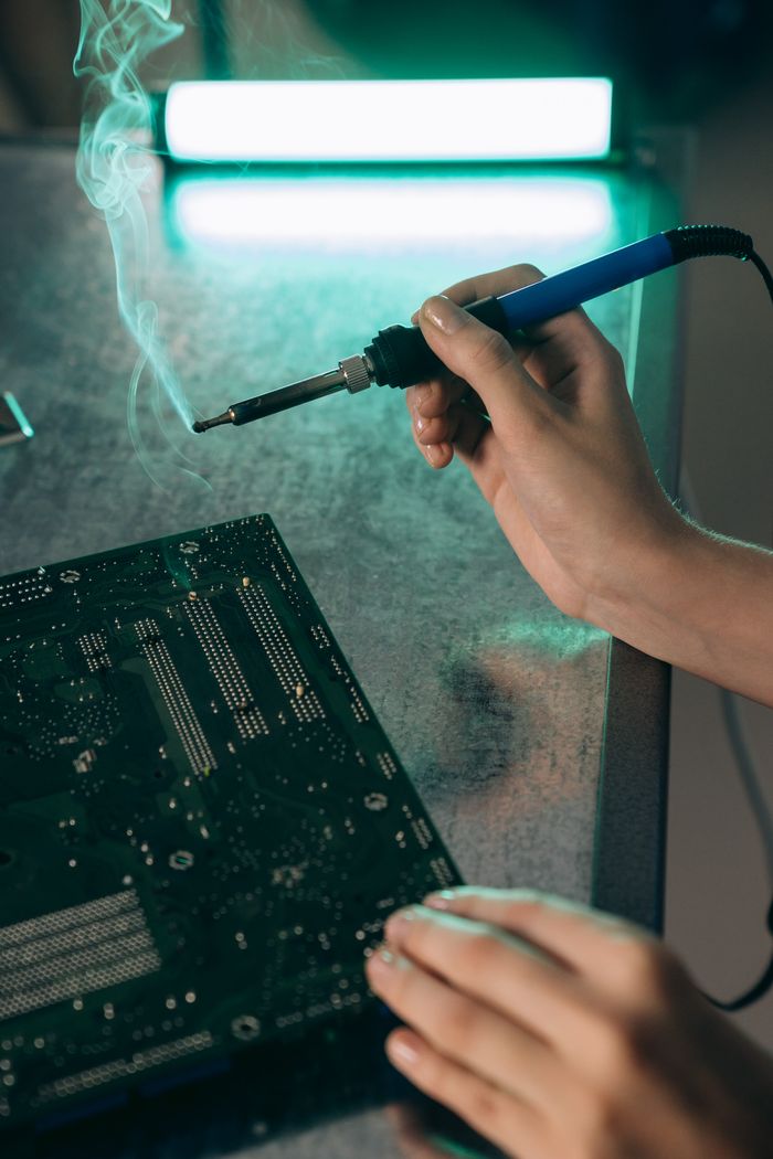 The Art of Drawing Readers In: Your attractive post title goes here Close-up of hands working on a motherboard with a soldering iron, producing smoke.
